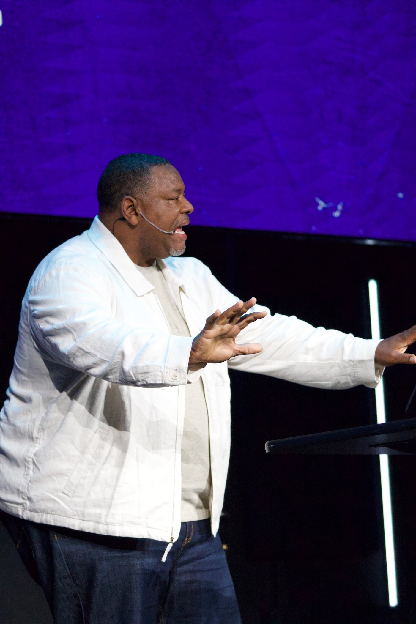 Gino Mingo teaching on stage with both hands extended