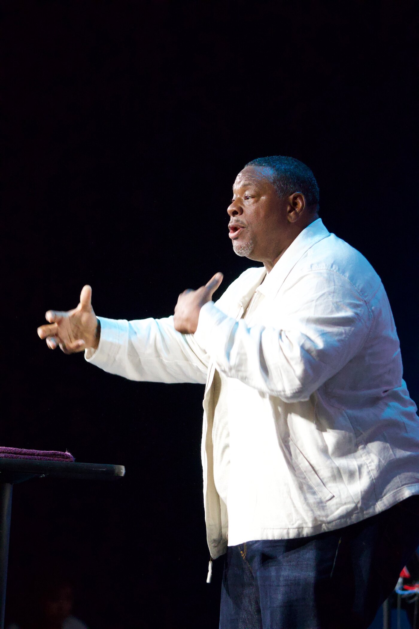 Gino Mingo speaking on stage with an open hand during a ministry event