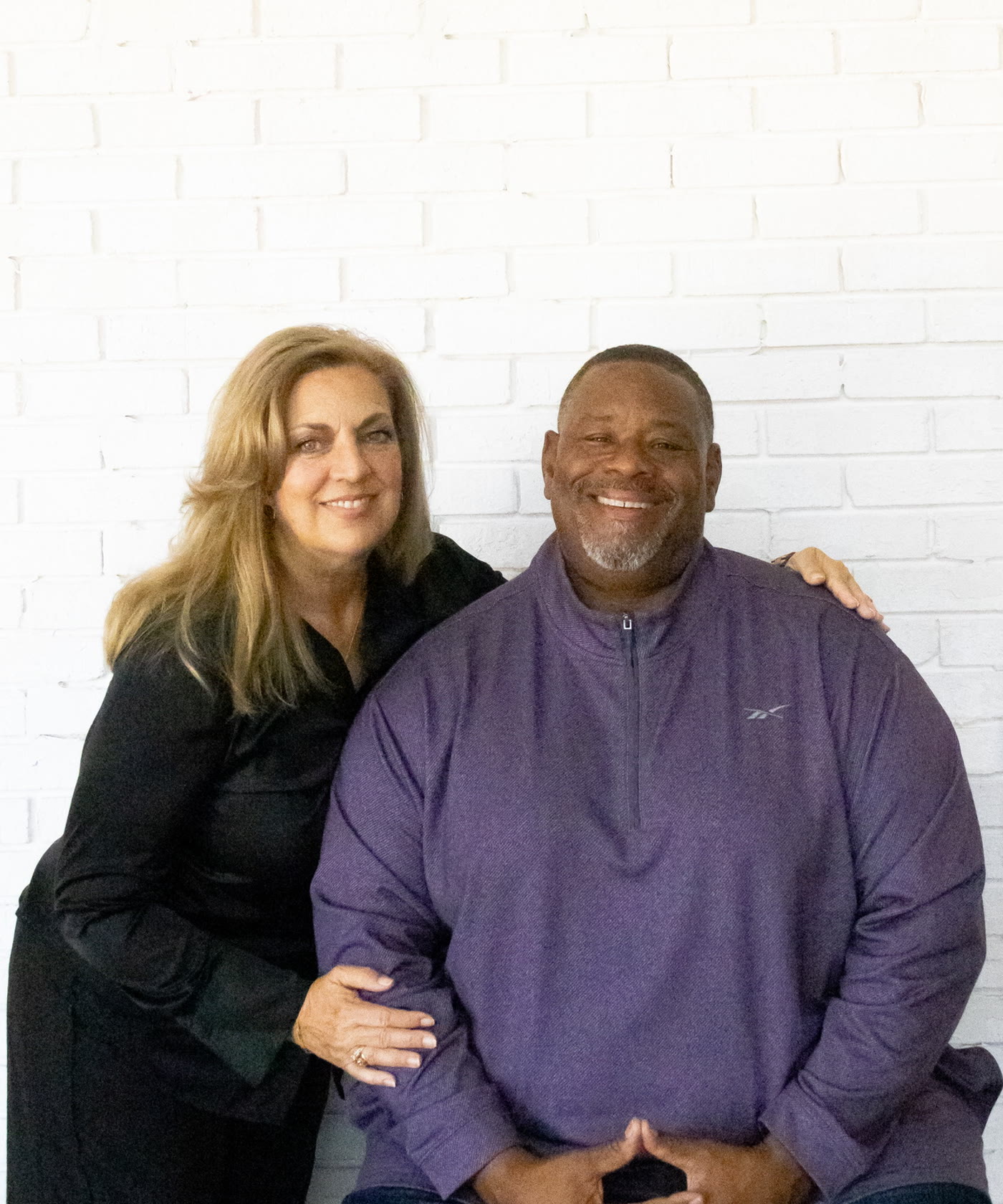 Gino and Michelle Mingo together against a white brick wall
