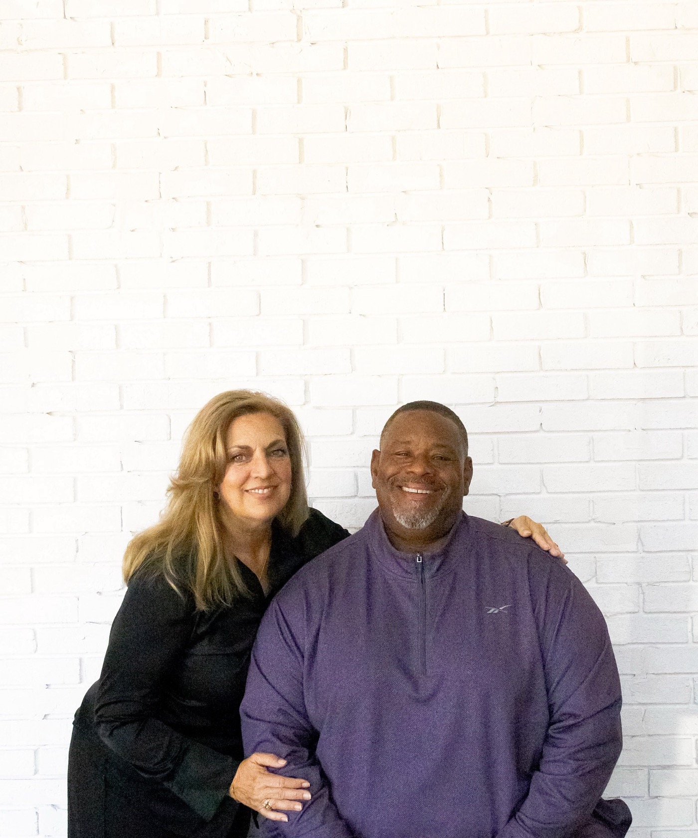 Gino and Michelle Mingo together against a white brick wall